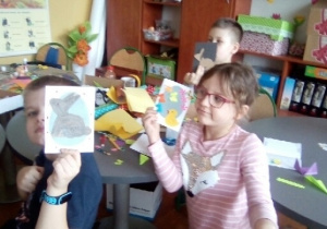 Dzieci pokazują samodzielnie wykonanie kartki wielkanocne.